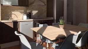Eine moderne Küche mit einem Holztisch und Stühlen, einem Geschirrspüler, einem Herd und einem Kühlschrank.