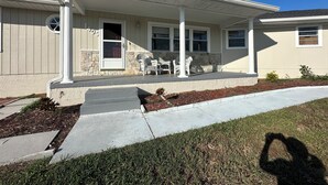 Une maison de plain-pied avec un porche couvert, des éléments décoratifs en pierre et le numéro « 405 » sur la porte.