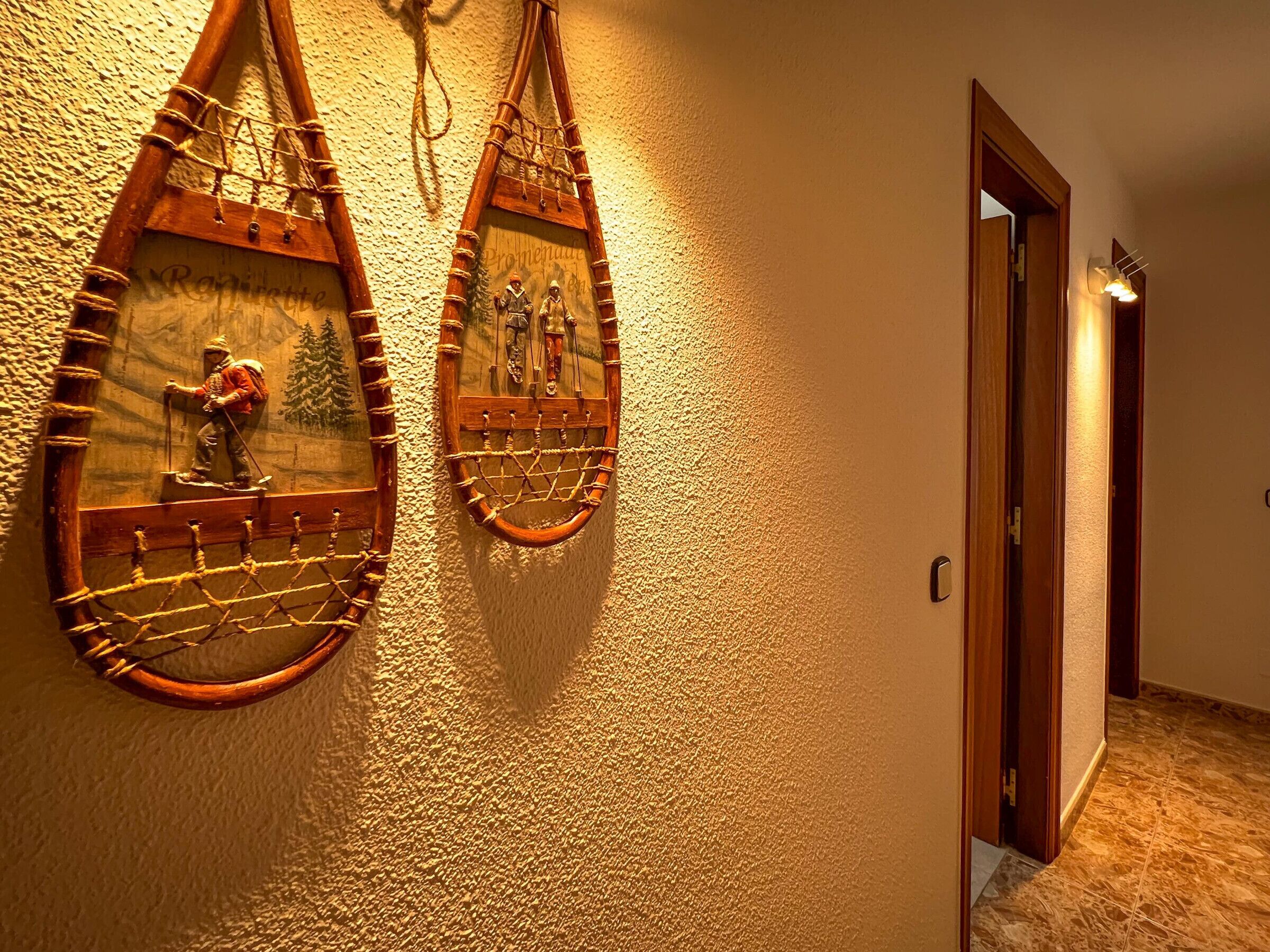 A hallway with two wooden wall decorations depicting skiers and a rope bridge.