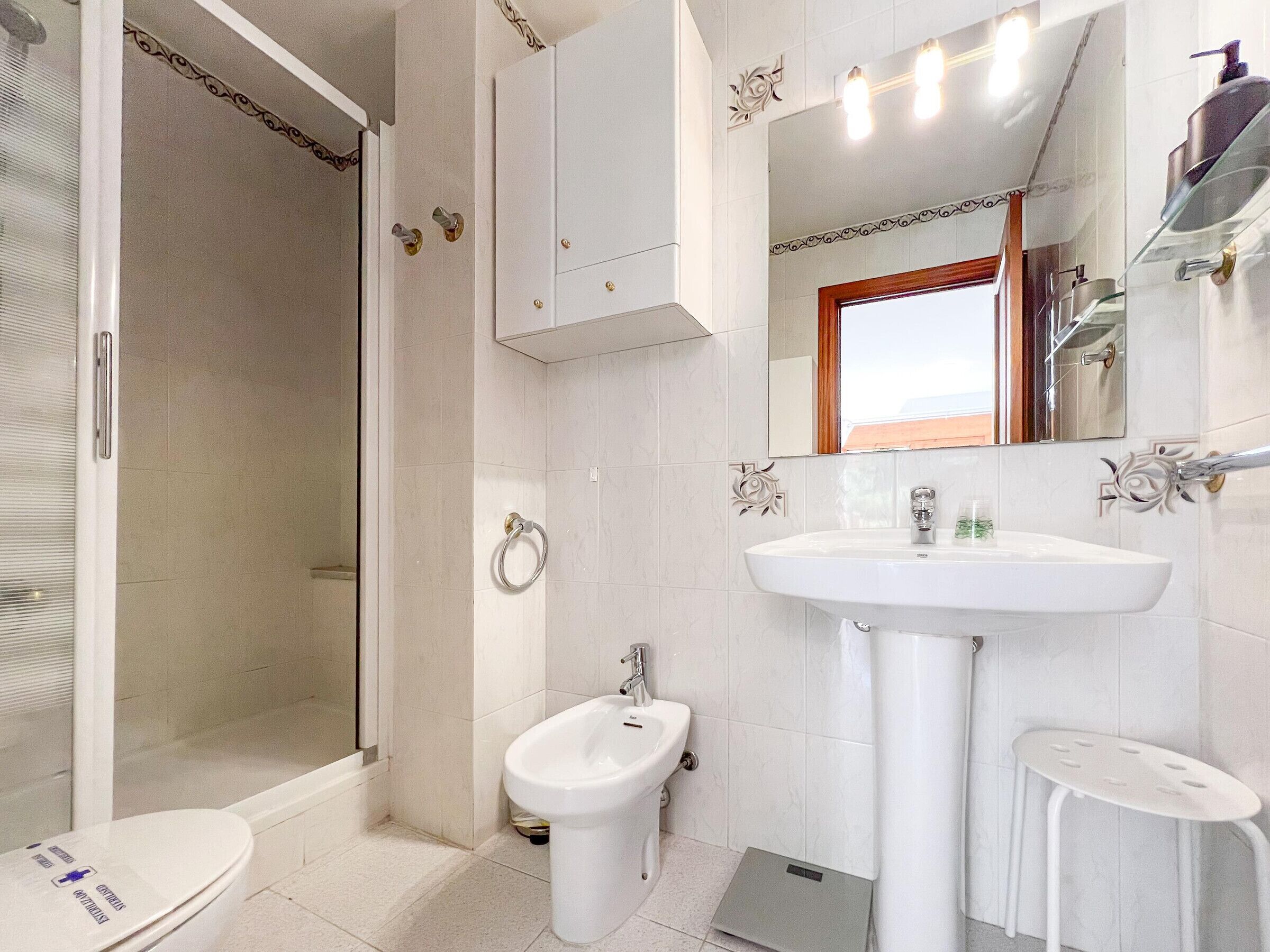 Une salle de bain équipée d’une douche, de toilettes, d’un bidet, d’un lavabo et d’un petit tabouret.