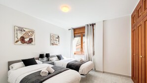 A bedroom with two beds, a window with curtains, and artwork on the wall. - Rider Apartment - 8 Guests, 4 Bedrooms (Pal)