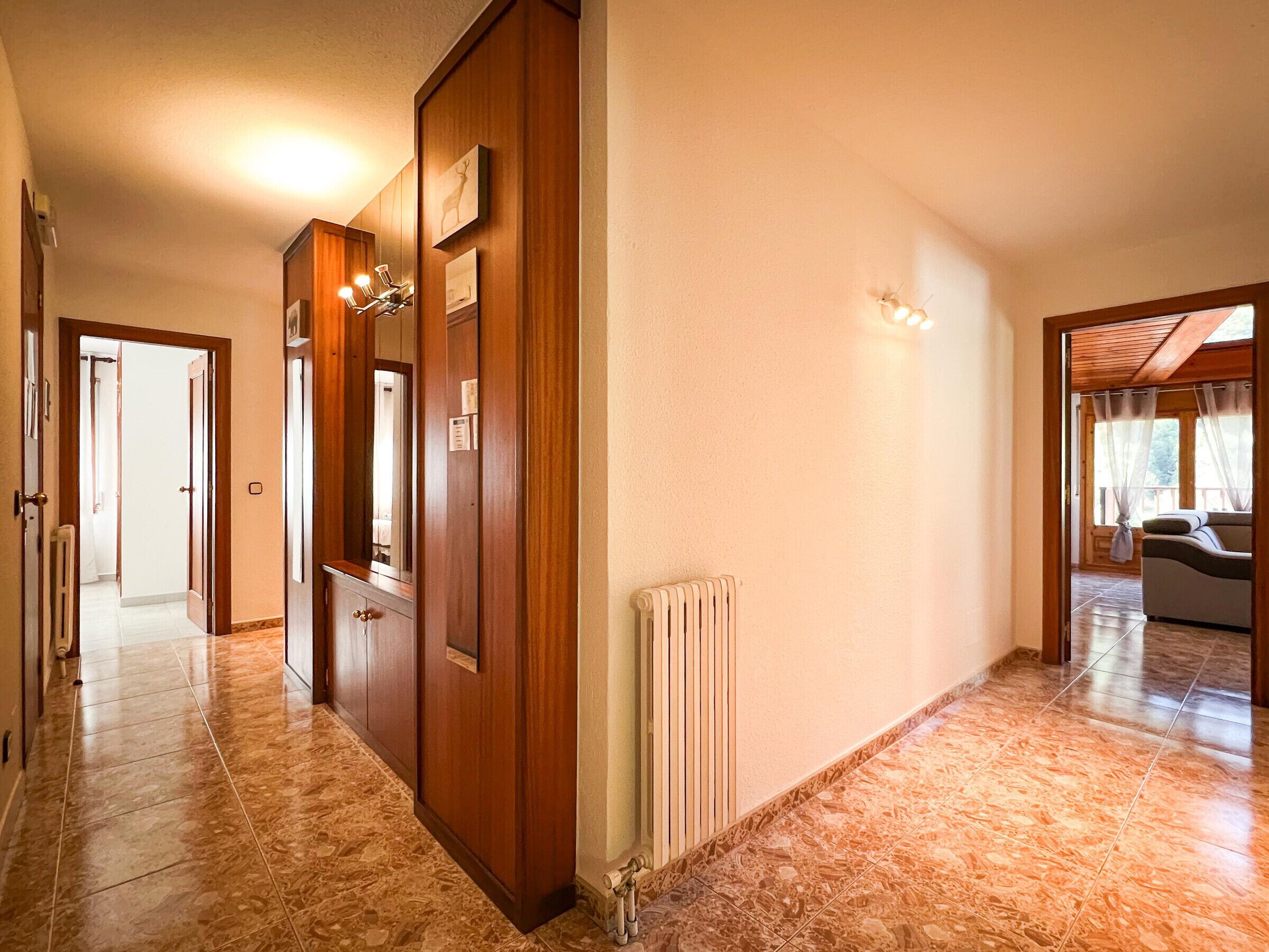 A hallway with wooden doors, a radiator, and a tiled floor.