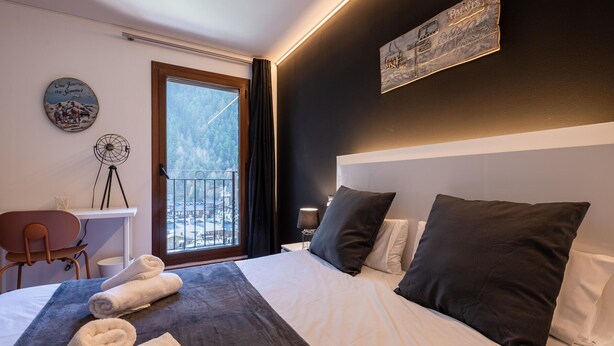 Ein Hotelzimmer mit Bett, Schreibtisch, Stuhl und Fenster mit Blick auf eine verschneite Landschaft.