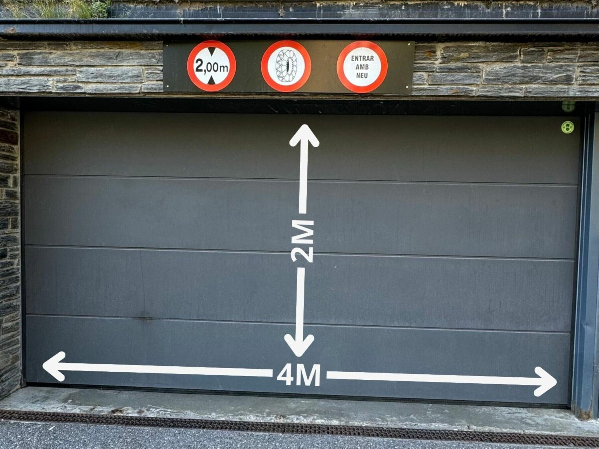 Un portone garage con frecce direzionali e un cartello con l'indicazione dell'altezza massima.