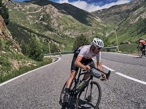 Un cycliste sur une route asphaltée, avec une chaîne de montagnes en arrière-plan.