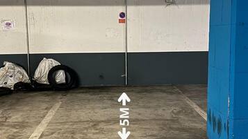 Un estacionamiento con paredes de hormigón, un pilar azul y una flecha direccional en el suelo.