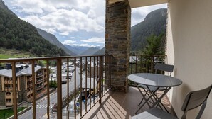 Ein Balkon mit Steinpfeiler, Tisch und zwei Stühlen.
