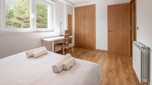 Ein Schlafzimmer mit einem Bett, einem Schreibtisch, einem Stuhl und zwei Holztüren.