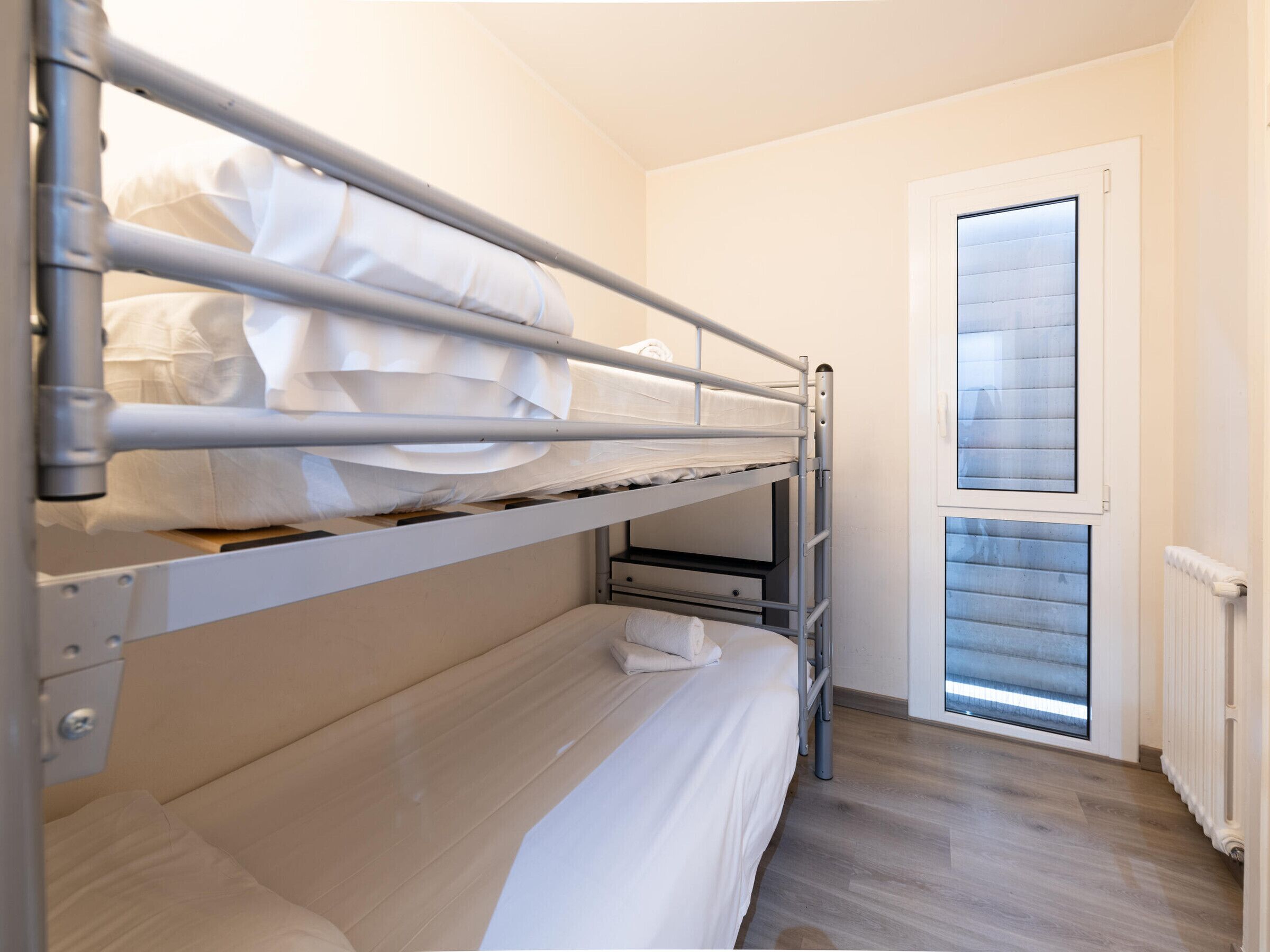 Habitación con literas, ventana y radiador.