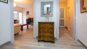 Un pasillo con un aparador de madera, un espejo con marco decorativo y un banco.
