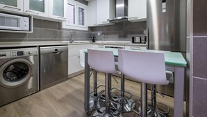 Una cocina moderna con electrodomésticos de acero inoxidable, microondas integrado y lavadora.