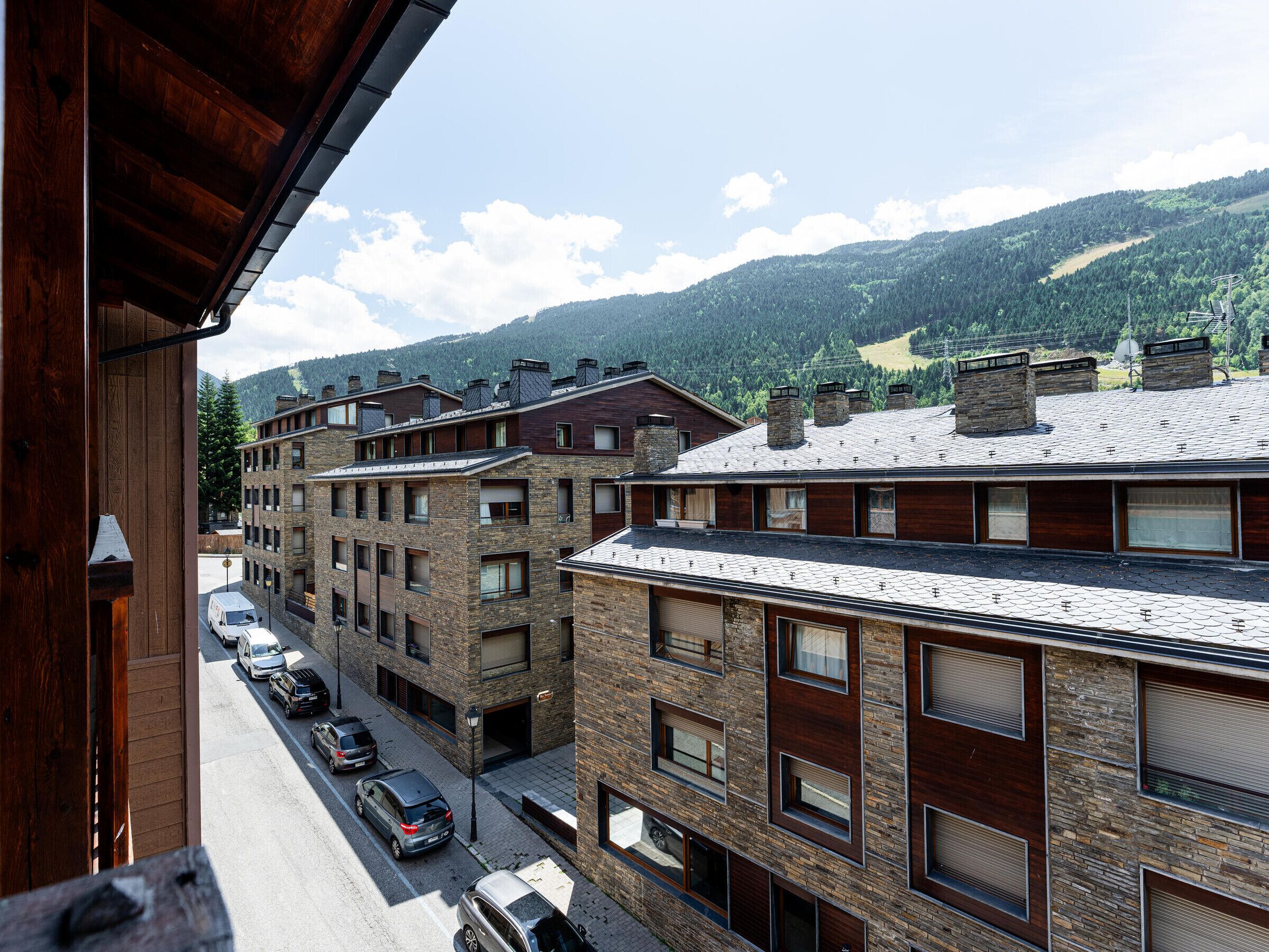 A multi-story building with a stone facade and a row of parked cars in front.