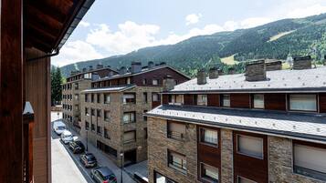 A multi-story building with a stone facade and a row of parked cars in front.