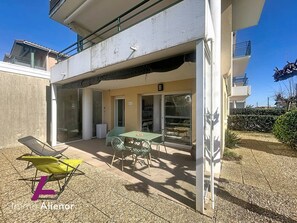 Une terrasse extérieure couverte, avec une table et des chaises, une chaise verte et une chaise jaune.