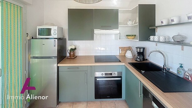 Una cocina compacta con microondas, horno y lavabo. Hay una lámpara colgante sobre la encimera.