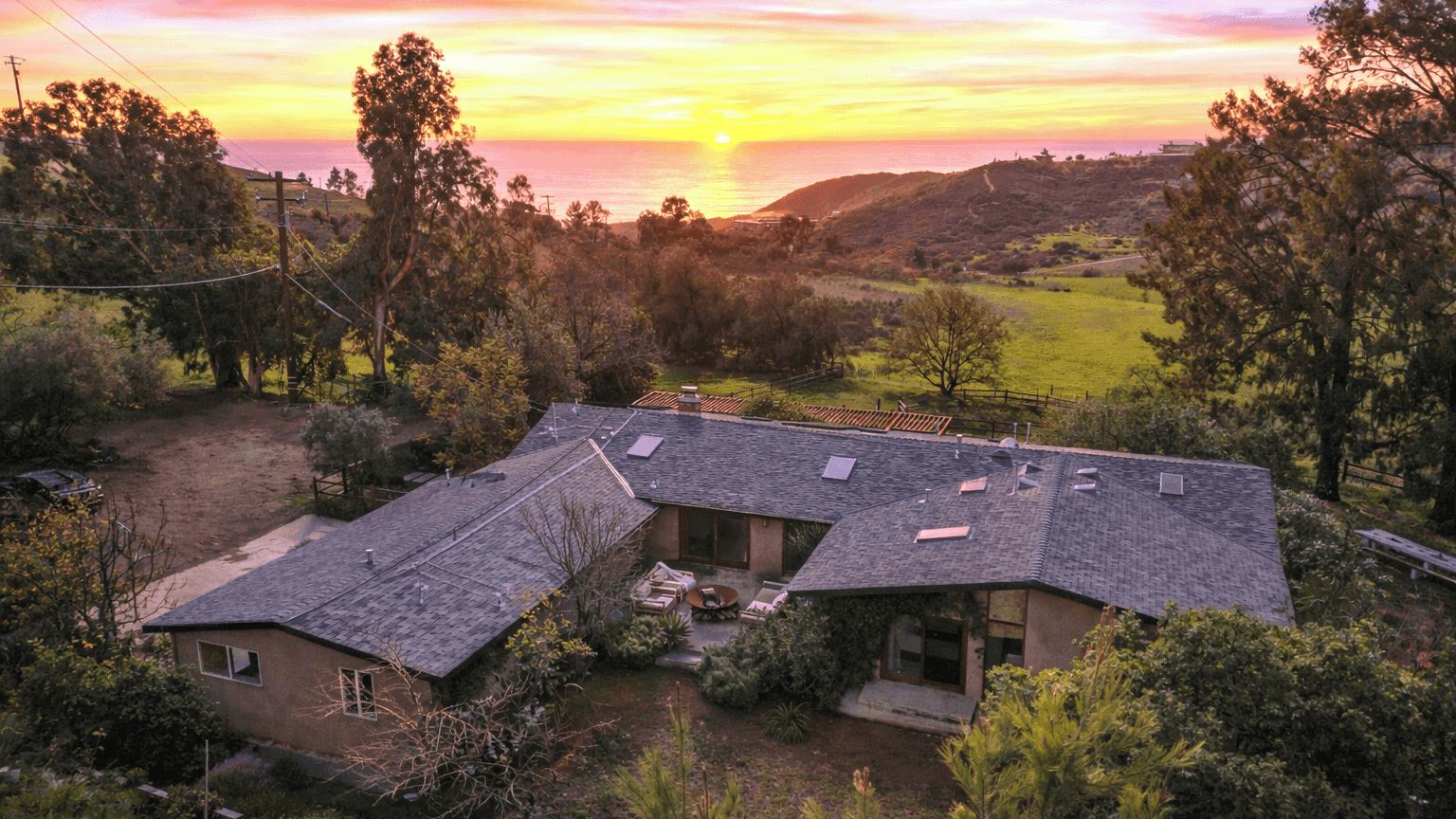 Uma casa com telhado inclinado, painéis solares e um espaço de varanda.
