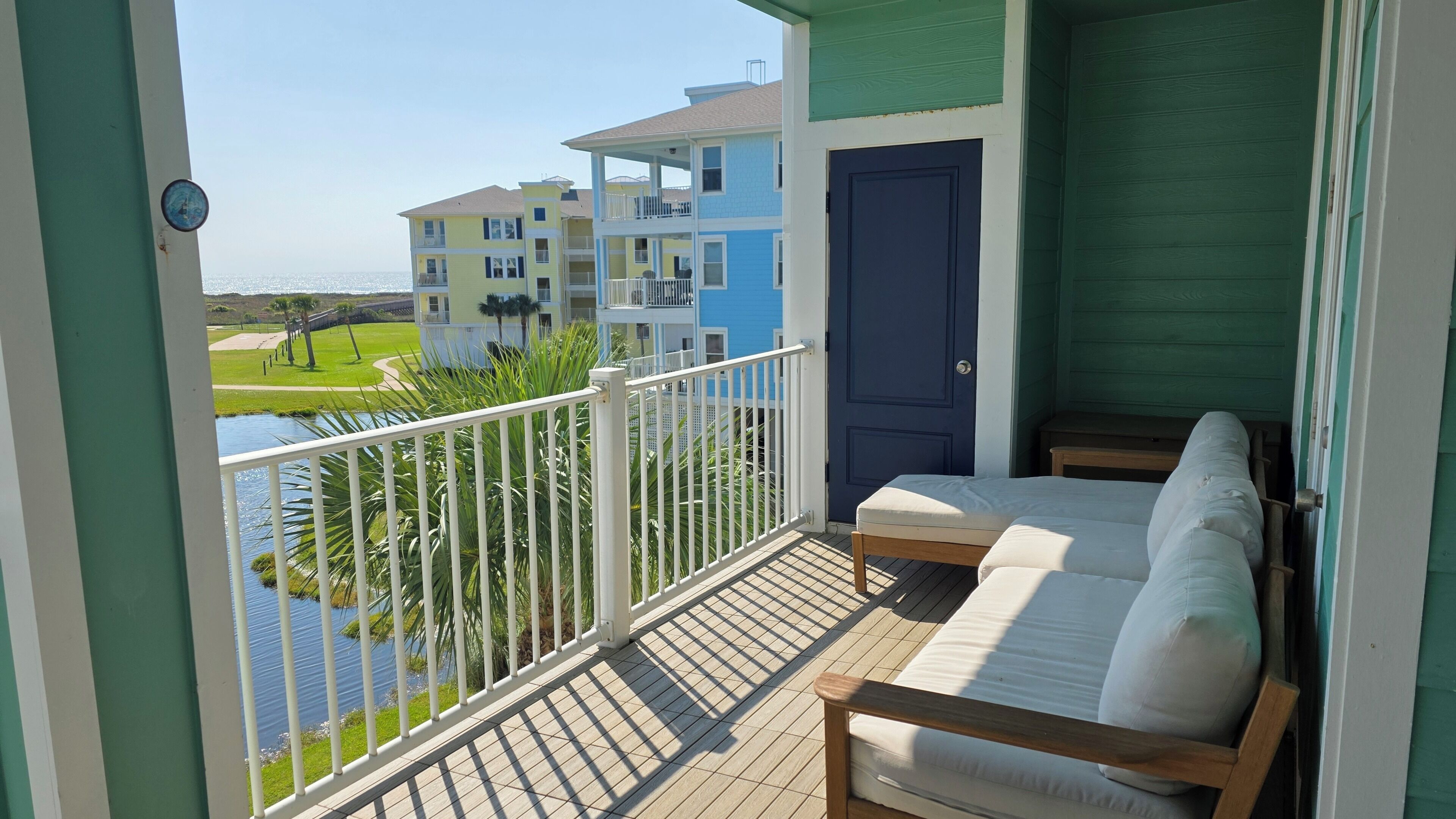 A balcony with a view of a water body and buildings, a door, and a small table.