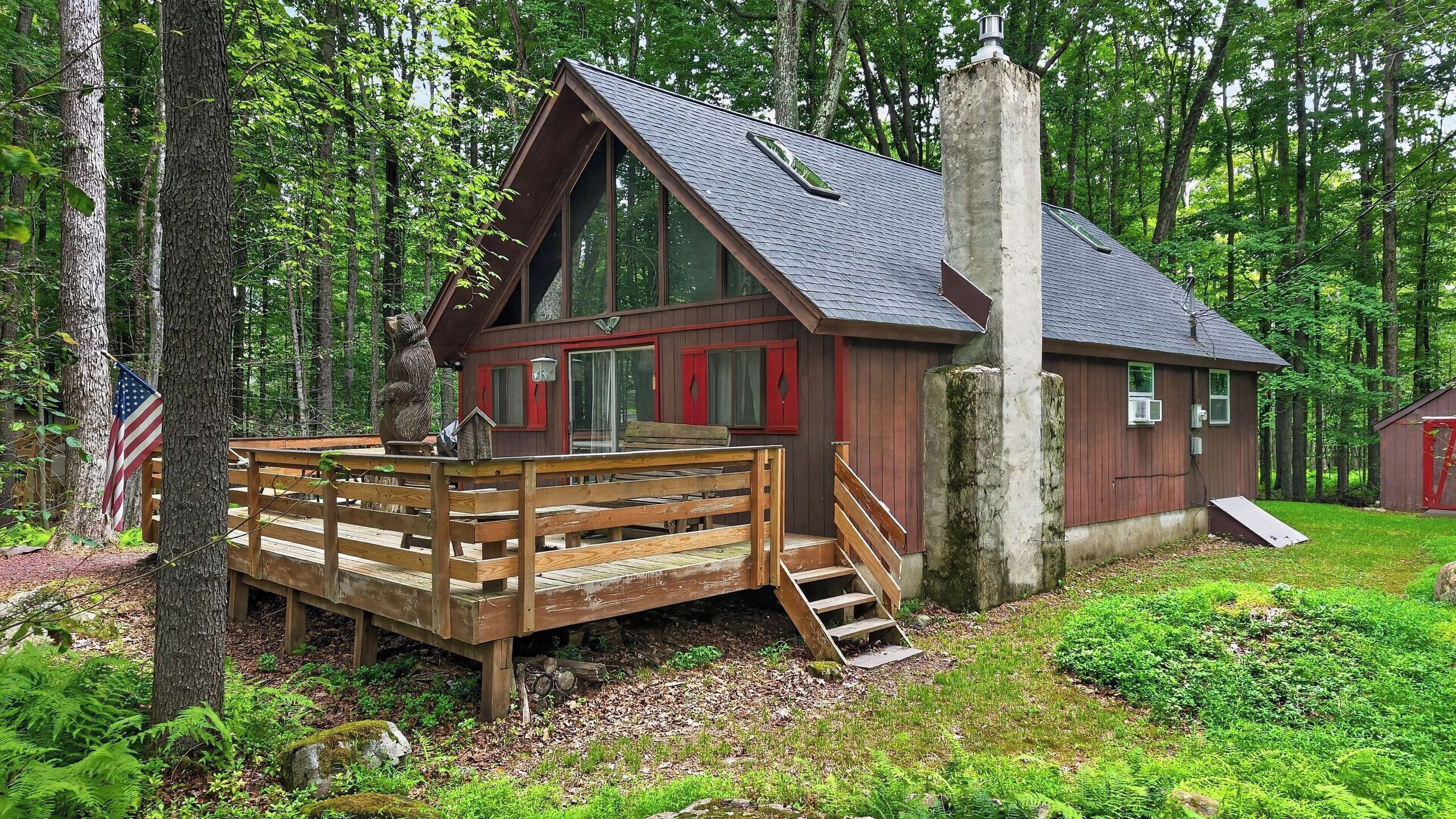 Eine Holzhütte mit einer Holzterrasse, einem Schornstein und einer roten Tür.