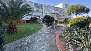 Un hotel de varios pisos con un patio central, que cuenta con un camino de piedra, palmeras y diversos arbustos.