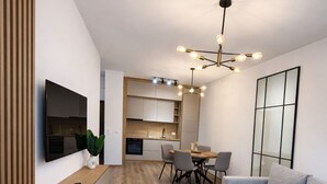 Un salon moderne comprenant un canapé, une table basse, un téléviseur et un coin repas avec des chaises et une table.
