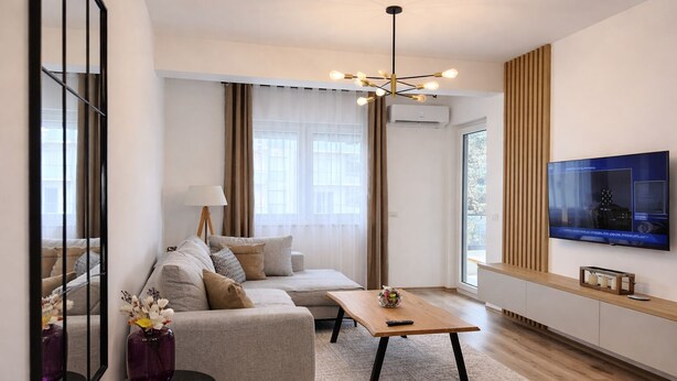 Un salon moderne avec un canapé, une table basse, un téléviseur et une grande fenêtre.