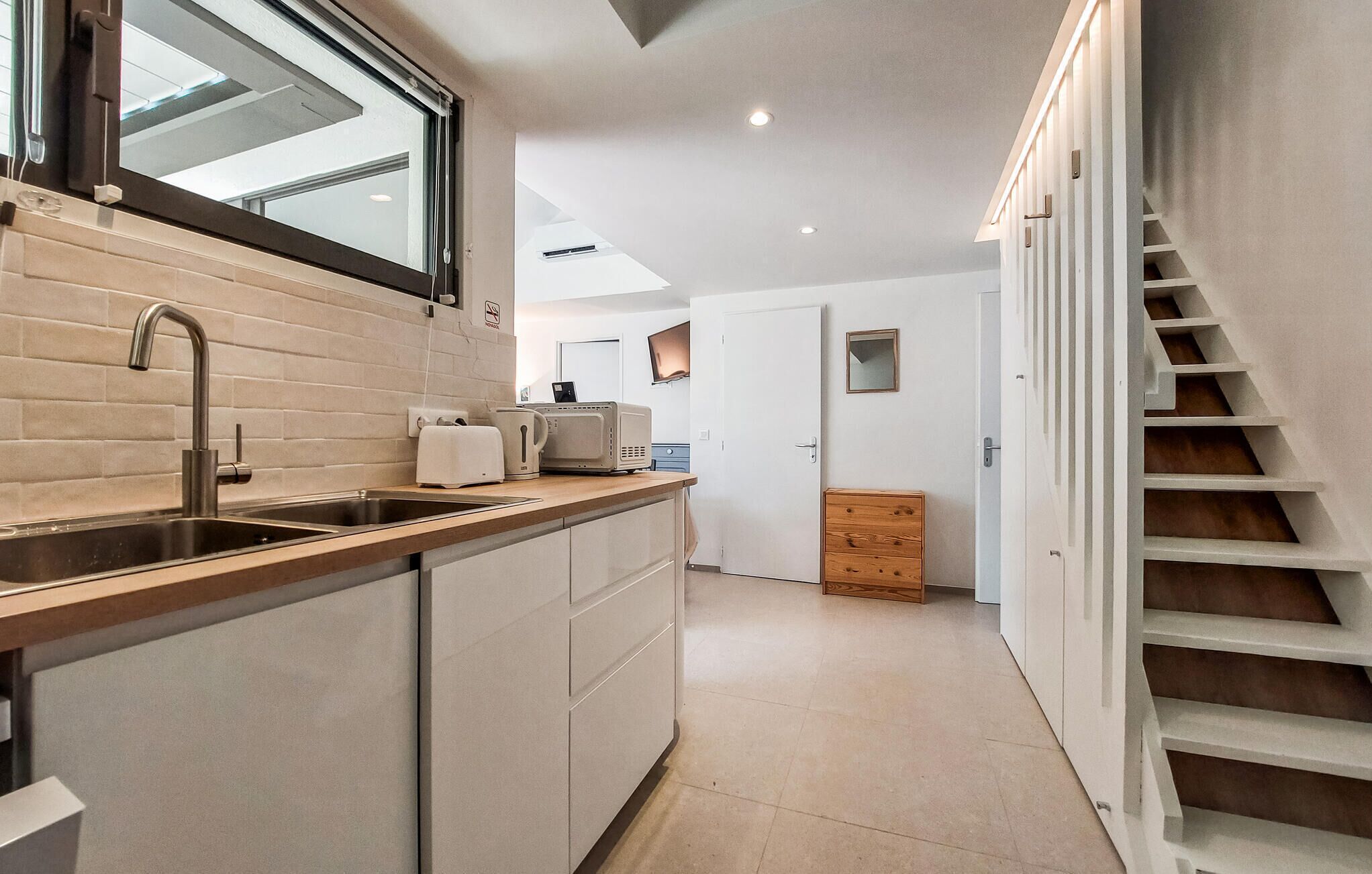 Een moderne keuken met een inbouwoven, een spoelbak en een raam boven het aanrecht.
