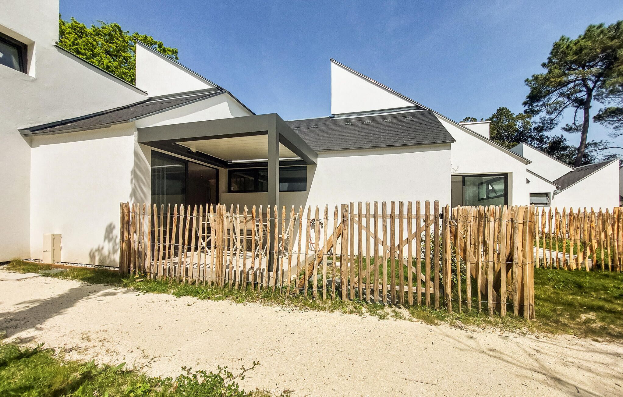 A modern house with a wooden fence, a covered patio, and a clear sky.