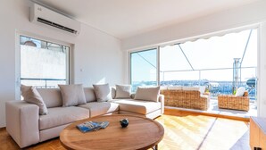 A modern living room with a sofa, a round coffee table, and wicker furniture. - Terrace Dreams w/Pasalimani View - 2 minutes of walk distance (Pireas)