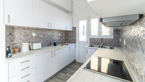 A modern kitchen with white cabinets, a stone backsplash, and a built-in stove. - Terrace Dreams w/Pasalimani View - 2 minutes of walk distance (Pireas)