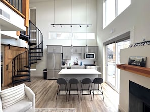 A modern kitchen with a central island, stainless steel appliances, and a view to the outside.