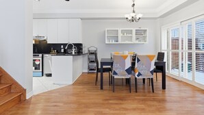 Eine moderne Küche mit weißen Schränken, einer schwarzen Arbeitsplatte und einem Essbereich mit Tisch und Stühlen.