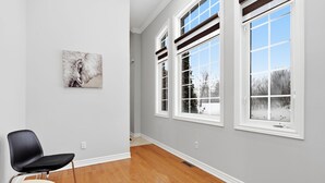 Ein Zimmer mit einem großen Fenster, einem Sessel und einem Tisch.