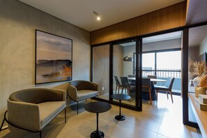Ein modernes Wohnzimmer mit einer Couch, zwei Sesseln, einem Couchtisch und einem Essbereich mit Stühlen und einem Tisch.