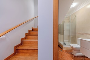 Un escalier menant à une salle de bain dotée d’une douche à parois en verre.