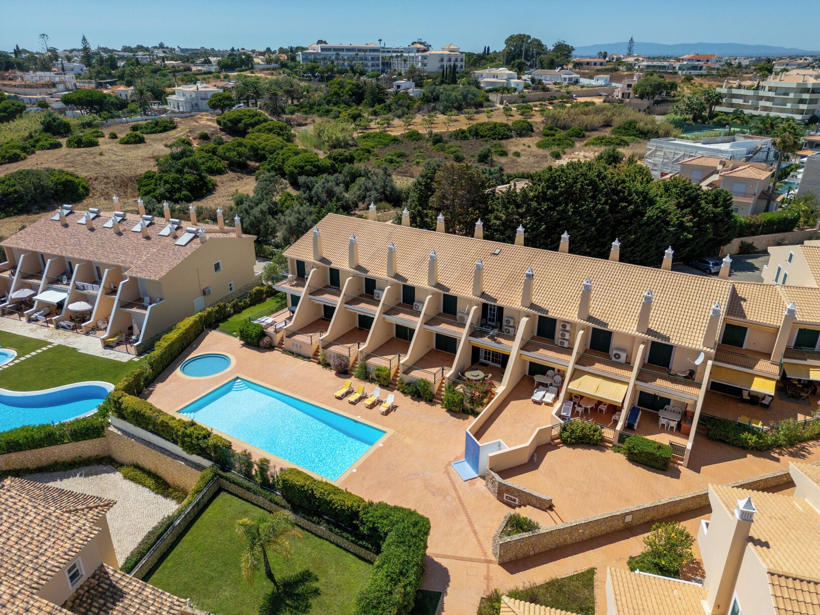 Um hotel com piscina, várias varandas e vista para a paisagem circundante.