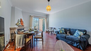 Una sala de estar con una mesa de comedor, sofá azul y chimenea.