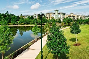 A residential area with a water body, green lawns, and multi-story buildings.