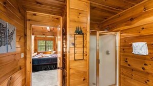 Ein Holzblockhaus-Interieur mit einem Bett, einer Schiebetür und einem kleinen Fenster.
