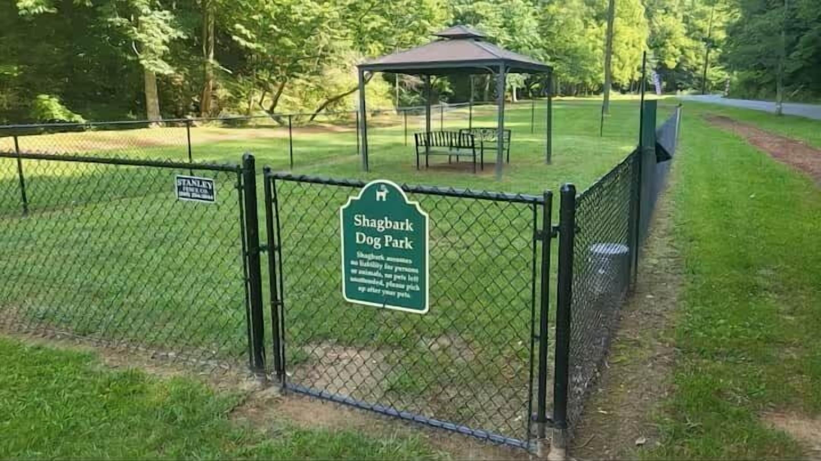 A fenced dog park with a gazebo and a sign indicating it is a Shagbark Dog Park.