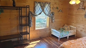 A wooden cabin room with a bunk bed, a ladder, a window with patterned curtains, and a ceiling fan. - Charming 1-bedroom house on 2 acres in peaceful Orrington (Orrington)