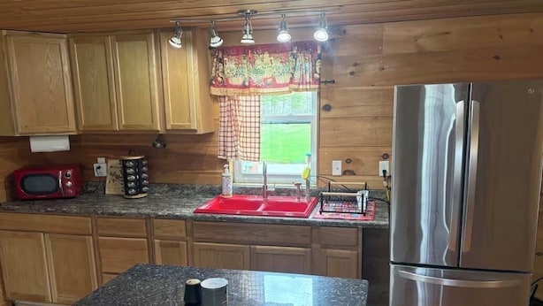 A kitchen with wooden cabinets, a stainless steel refrigerator, a red sink, and a granite countertop. - Charming 1-bedroom house on 2 acres in peaceful Orrington (Orrington)