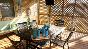 Una terraza de madera con una mesa, sillas y un banco, además de una valla decorativa.