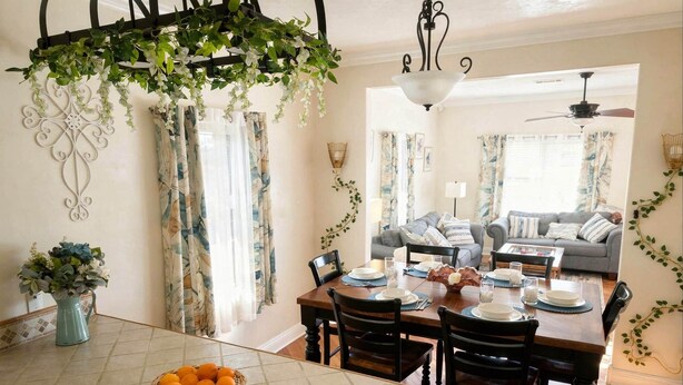 Un comedor con mesa lista para cuatro, una araña y vista al salón.