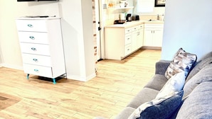 A living room with a grey sofa, a flat-screen TV, and a white cabinet with drawers. - Charming downstairs unit Walking Distance to the Beach! (Galveston)