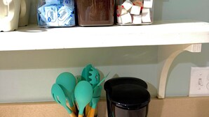 A kitchen shelf with storage containers, a coffee maker, and kitchen utensils. - Charming downstairs unit Walking Distance to the Beach! (Galveston)