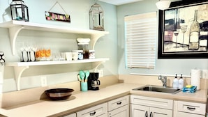 A kitchen with white cabinets, a wooden countertop, a coffee maker, and a window with blinds. - Charming downstairs unit Walking Distance to the Beach! (Galveston)