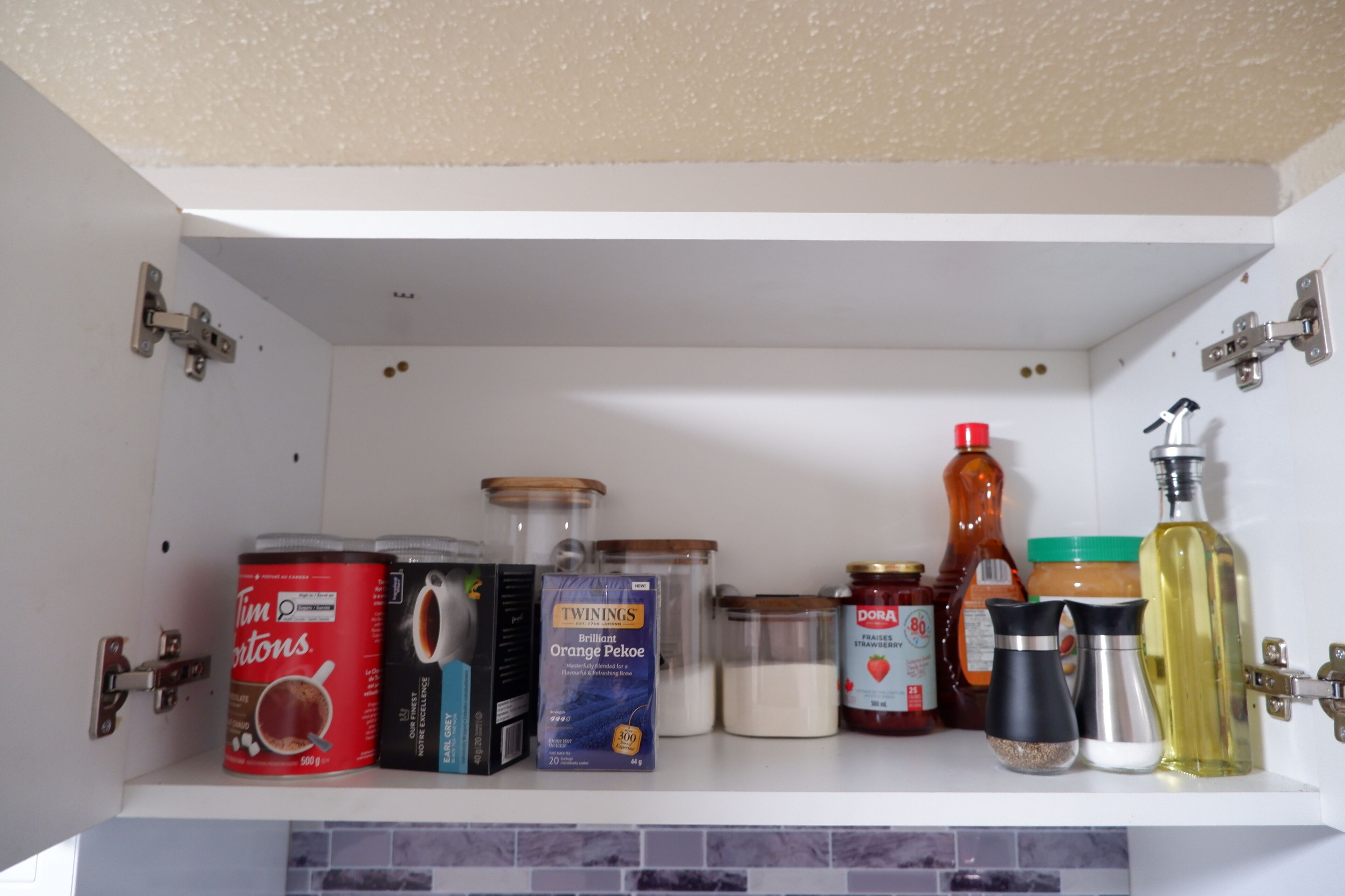 A kitchen pantry with various food items and containers, including canned goods, jars, and bottles.