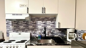 A kitchen with a white stove, a sink, and a coffee maker. - Cozy&Private Basement Suite. Minutes from Airport, Highway, College, Restaurants (Thunder Bay)