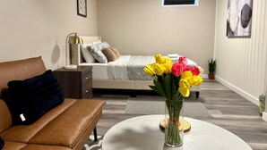 A bedroom with a bed, bedside table, lamp, and a vase of flowers. - Cozy&Private Basement Suite. Minutes from Airport, Highway, College, Restaurants (Thunder Bay)