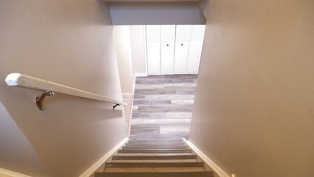 A staircase with wooden steps and white walls leading to a room with a closet. - Cozy&Private Basement Suite. Minutes from Airport, Highway, College, Restaurants (Thunder Bay)